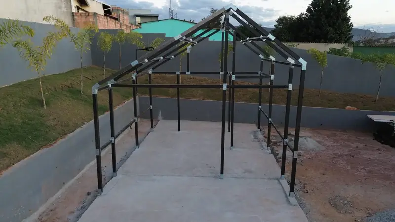 Estrutura metálica de uma casa EASY montada sobre base de concreto, com pilares, vigas e tesouras em tubos escuros